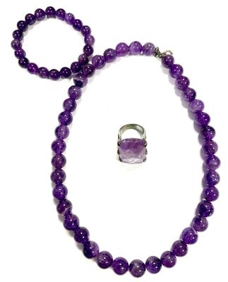 a close up of a purple necklace and bracelet with a ring