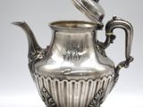 an antique silver tea pot with a lid on a stand
