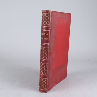 un vieux livre rouge posé sur une table à côté d'un mur blanc