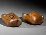 pair of carved wooden shoes with initials on them sitting on a table