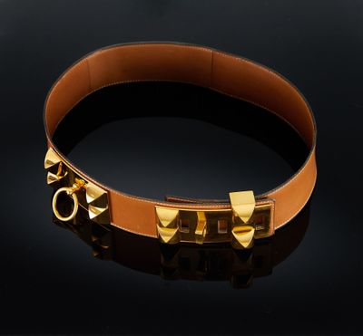 un bracelet en cuir marron orné de rivets dorés sur fond noir