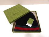 une boîte verte avec un chapeau noir et un chapeau rayé de rouge et de vert