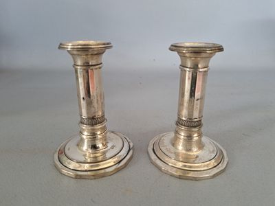 pair of silver candlesticks on a table with a white background