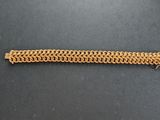 gros plan d'un bracelet en chaîne en or sur une surface noire