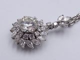 a close up of a diamond pendant on a chain on a white surface