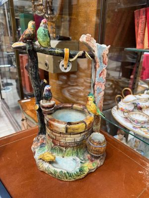 a figurine of a bird drinking water from a fountain