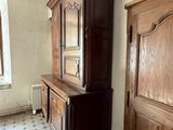 a wooden cabinet in the corner of a room with a tiled floor