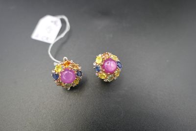 deux paires de boucles d'oreilles roses et jaunes posées sur un fond noir