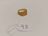 une bague en or posée sur une surface blanche, avec une étiquette de prix