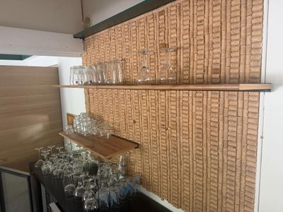 bottles and glasses are lined up on a shelf in a room