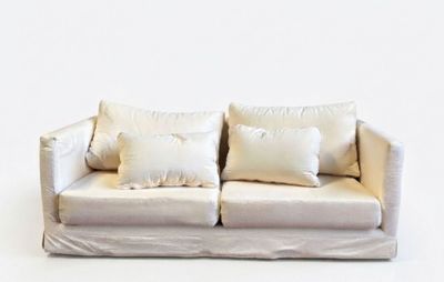 a white couch with pillows on it against a white wall
