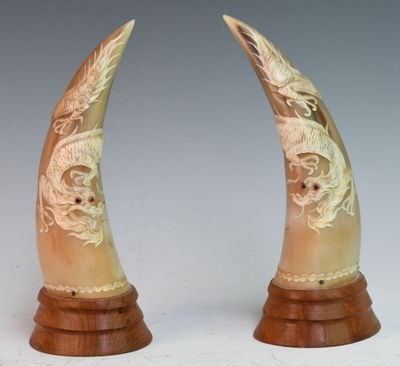 two horns with carvings on them on a wooden stand