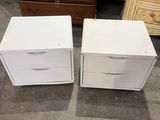 deux tables de chevet blanches à tiroirs et une commode à l'arrière-plan
