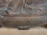 a bronze statue of a woman sitting on a bench