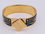 a close up of a gold bracelet with a black and blue design