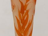 un vase orange et blanc posé sur une table en bois, sur fond blanc