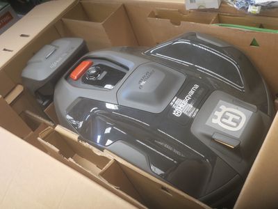 une tondeuse à gazon noire et grise à l'intérieur d'un carton