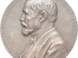 une image représentant une médaille d'argent sur laquelle figure le visage d'un homme