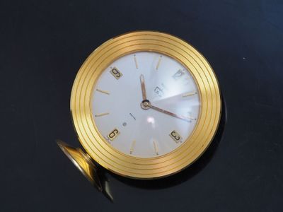 a gold clock sitting on a black table with a black background