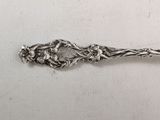 a silver spoon with flowers on it sitting on a table