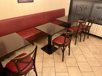 une table et des chaises dans un restaurant, avec une enseigne accrochée au mur