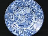 blue and white plate with a design of birds and flowers on it