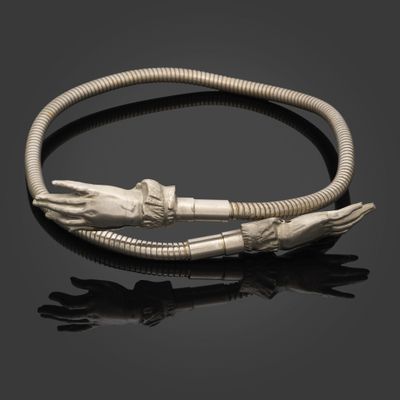 un bracelet en argent orné de deux mains et d'une tête de serpent sur un fond noir