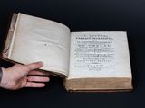 quelqu'un tient un vieux livre ouvert sur une surface noire