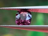 Quelqu'un est en train de tailler un diamant rose à l'aide d'une paire de pinces.