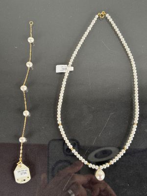 two necklaces and a pair of glasses are on display in a glass case