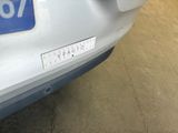 a white car with a blue number plate on it