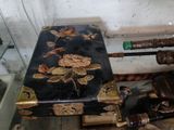une valise noire ornée de fleurs dorées, à côté d'une paire de parapluies