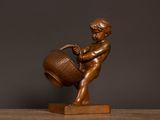 bronze statue of a boy with a bucket on a wooden base