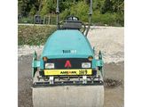 an image of a blue road roller sitting on top of a gravel road