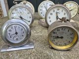 many different clocks sitting on a table in a row