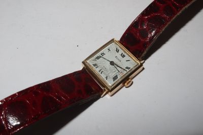 a red strap around a watch on a white surface