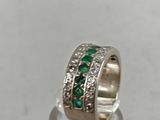 a close up of a ring with green stones and diamonds