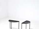 deux tables noires posées l'une à côté de l'autre sur un sol blanc
