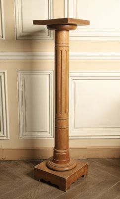 un socle en bois surmonté d'un plateau en bois, placé dans un coin de la pièce
