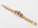 a gold bracelet with amethtites and purple stones