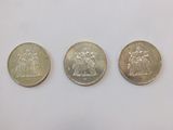 three different british coins sitting side by side on a white surface