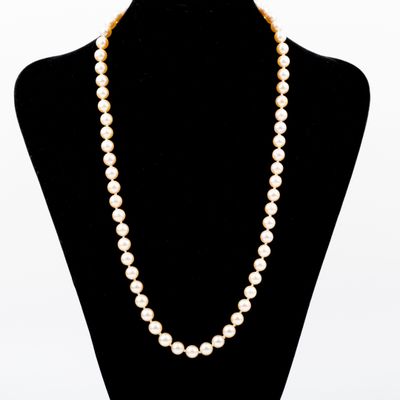 a white pearl necklace on a mannequin with a gold clasp