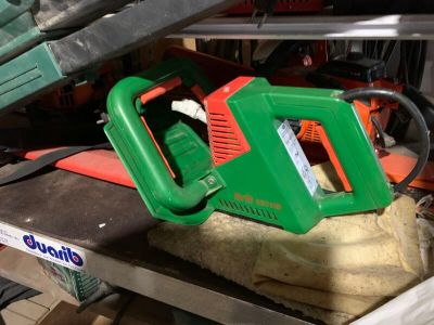 une tronçonneuse verte et orange posée sur une table