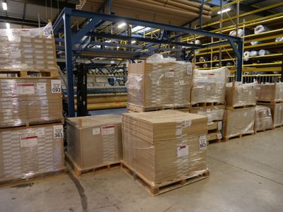 boxes are stacked on pallets in a large warehouse area