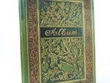 an old book with a gold and green cover on a white background