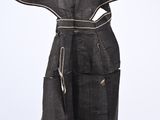 a black dress hanging on a hanger on a white wall