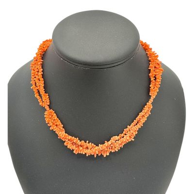 un gros plan d'un collier orné de perles orange sur un mannequin