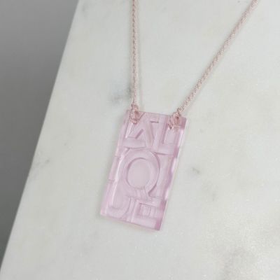 Collier en acrylique rose orné d'un motif géométrique, monté sur une chaîne dorée