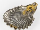 silver and gold shell shaped dish with a dragon on it