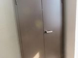 une armoire métallique placée dans un coin de la pièce, sur laquelle se trouve une poubelle rouge